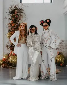 three women in white outfits standing next to each other with fake flowers on their heads