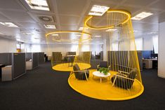 an office cubicle with chairs, tables and yellow spiral lights hanging from the ceiling