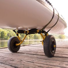 a large white boat sitting on top of a wooden dock next to the water and trees