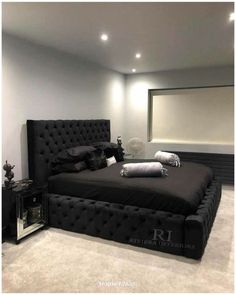 a black bed sitting in the middle of a room next to a wall mounted mirror