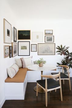 a white room with pictures on the wall and a bench in front of it,