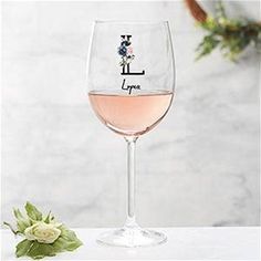 a wine glass filled with pink wine sitting on top of a table next to flowers