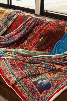 a multicolored blanket sitting on top of a wooden table next to a window