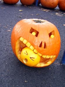 an orange pumpkin with a face carved into it's mouth and eyes, on the ground