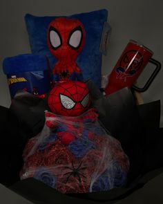 a spiderman pillow and some other items in a black bag with blue pillows on it