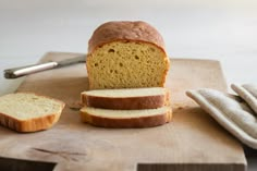 a loaf of bread sitting on top of a cutting board next to two slices of bread