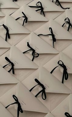 many pieces of paper with black ribbon tied around them on top of each other in rows