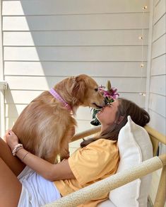 a woman laying in a chair with a dog on her lap and wearing a flower crown