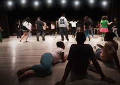 group of people sitting on the floor in front of a stage full of people dancing