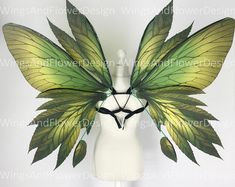 a white mannequin headdress with green leaves on it's wings