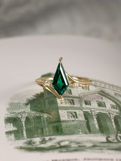 an emerald colored ring sitting on top of a white plate