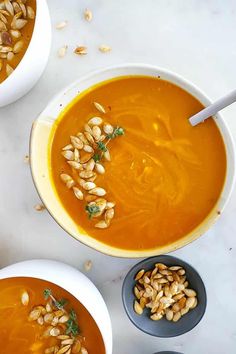 three bowls filled with soup and nuts on top of a white countertop next to each other