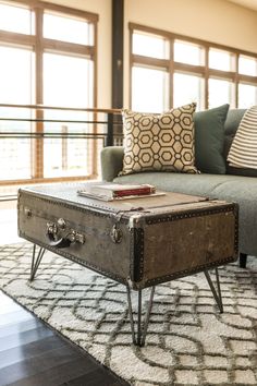 an old trunk coffee table is sitting on a rug in front of a couch and window