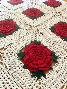 a crocheted blanket with red flowers on it