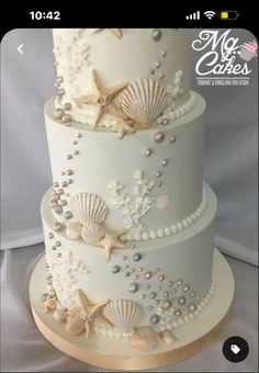 a three tiered wedding cake with seashells and pearls