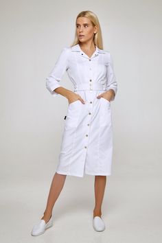 This fashionable uniform dress will make any female doctor or a beautician look stylish and classy when at work. The medical lab coat has a comfortable midi length fitted silhouette and 3/4 sleeves. It fastens with golden tone buttons of matte texture. A turn-down collar, deep vertical pockets, and topstitching make the silhouette more elegant and slender. The dress is complemented with a detachable belt with an elastic insert and a snap fastener. The fabric is 70% cotton, 30% polyester, made in Nanny Outfit, Nurse Dress Uniform, White Scrubs, Doctor Dress, Scrubs Dress, Medical Lab, Farm Dress, Doctor Outfit, Lab Coats