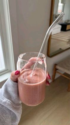 a person holding a glass with a smoothie in it and a straw sticking out of the top