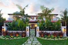 a large house with lots of palm trees in the front yard and walkway leading to it