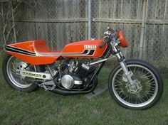 an orange and black motorcycle parked in the grass