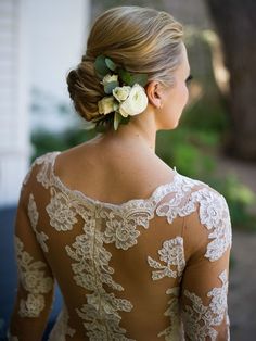 a woman with flowers in her hair is wearing a wedding dress and looking off into the distance