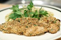 a white plate topped with meat covered in gravy and garnished with parsley