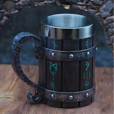 a metal mug with green arrows painted on the outside and inside, sitting on a wooden table