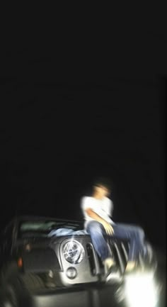 a man sitting on top of a car in the dark