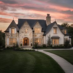 a large house that is sitting in the middle of a grass covered field at sunset