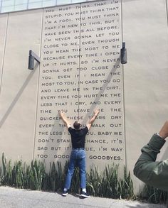 a man standing in front of a wall with writing on it and two people taking pictures