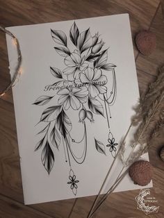 a drawing of flowers and feathers on top of a wooden table next to some feathers