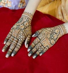 a woman's hands with hennap on it sitting on a red blanket