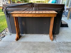 a wooden table sitting on top of a patio next to a hot tub in the back yard