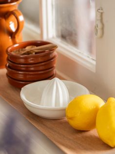 two lemons and a bowl sit on a counter next to some plates with food in them