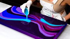 a woman in white gloves painting a purple and blue design