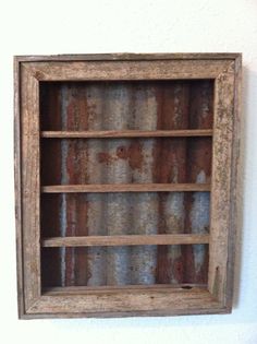 an old wooden shelf is hanging on the wall with rusted paint and wood trim