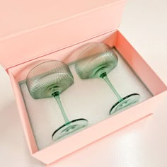 two green glasses sitting in a pink box