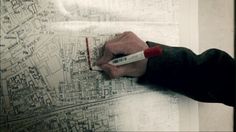 a person is writing on a map with a marker and red pen in their left hand