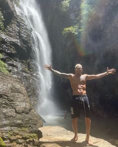 a man standing in front of a waterfall with his arms wide open and hands out