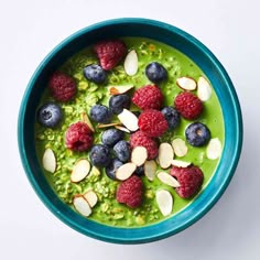 a bowl filled with green smoothie topped with raspberries and almonds