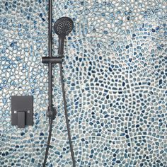 a shower head and hand held shower faucet with mosaic tiles on the wall