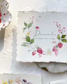 watercolor flowers and leaves on white paper with the words december written in cursive writing