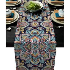 the table runner is decorated with blue and green paisley designs, along with white plates