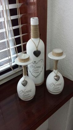 three white wine bottles sitting on top of a wooden shelf in front of a window