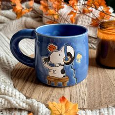 a blue coffee mug with a cartoon dog on it sitting next to a jar of hot chocolate