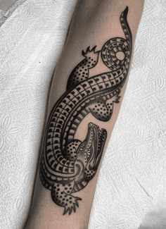 a black and white photo of a lizard tattoo on the left arm, with an intricate design