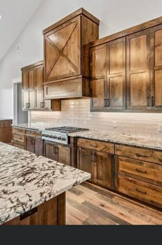 a large kitchen with wooden cabinets and marble counter tops in the middle of an open floor plan