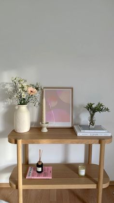 a wooden table topped with a vase filled with flowers next to a book and candle