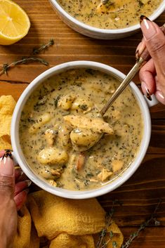 two bowls of chicken and dumpling soup on a wooden table with lemons in the background