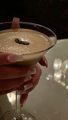 a person holding a drink in their hand with some liquid on the rim and gold flecks