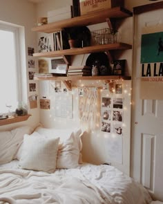 a bed with white sheets and pillows in a bedroom next to a window filled with lights